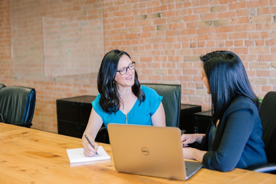 Two colleagues reviewing work together on a laptop in a bright office