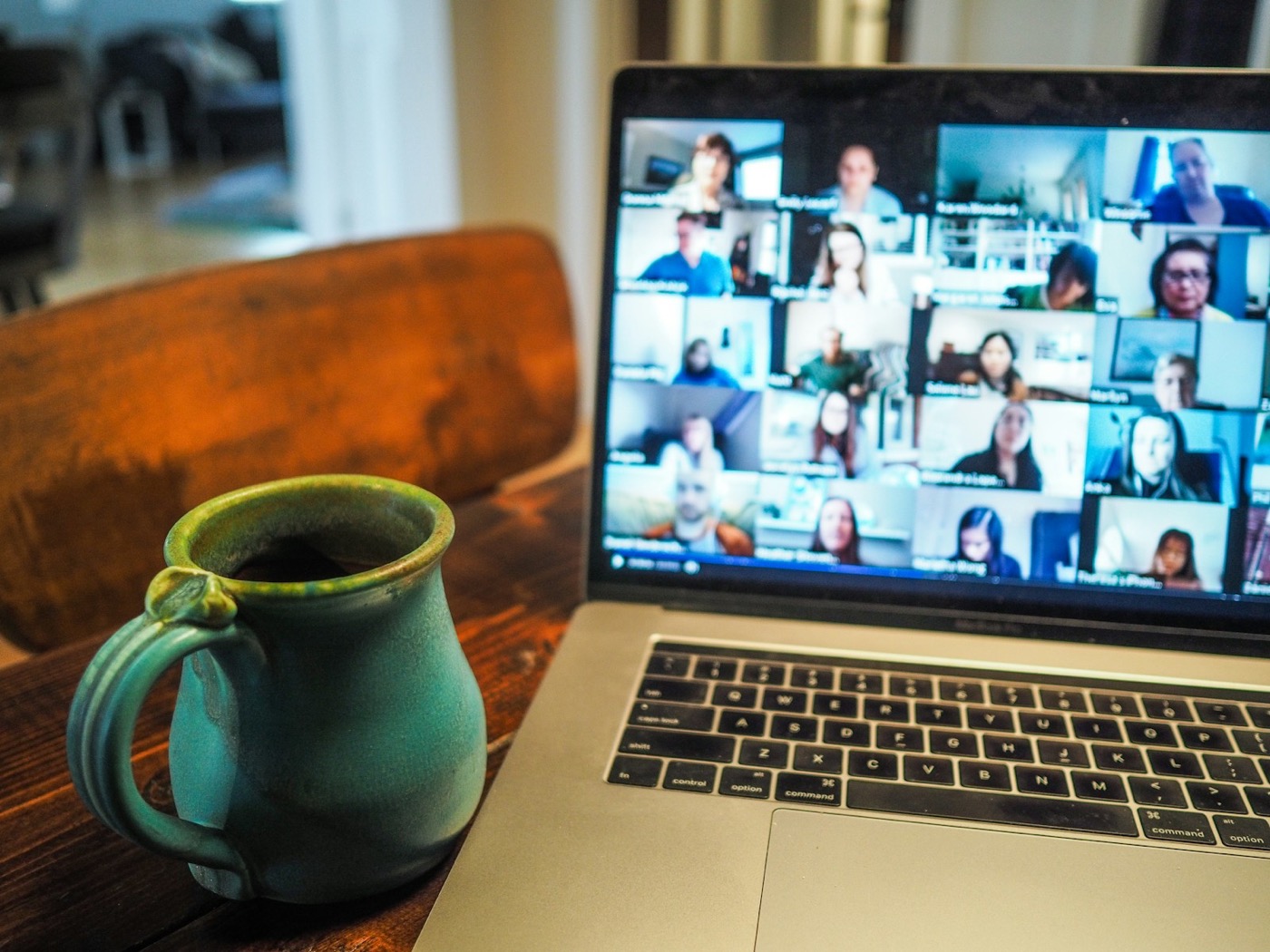Remote video meeting with colleagues on a laptop at a wooden table