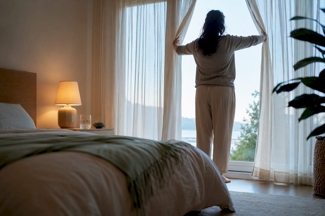 Person opening curtains at consistent wake time